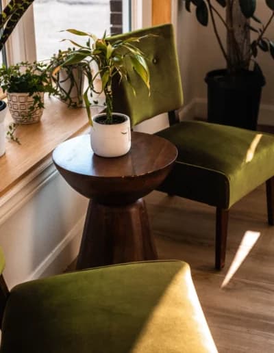 Waiting area with green chairs and a round walnut table